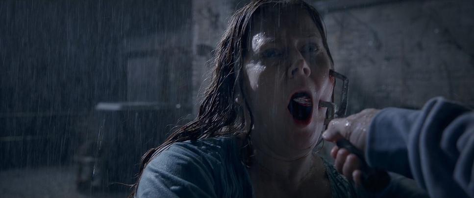 A woman screaming in the rain, a blade held at her cheek